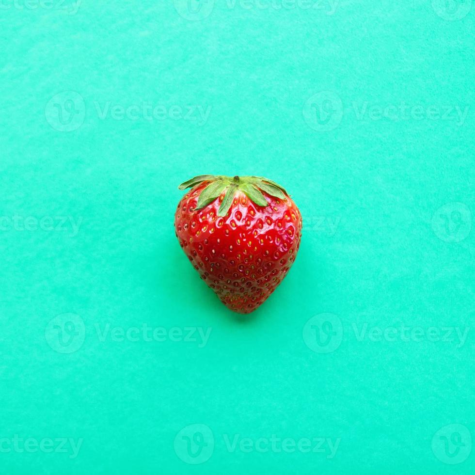 fresa roja madura sobre un fondo turquesa, vista superior. comida saludable de verano. foto