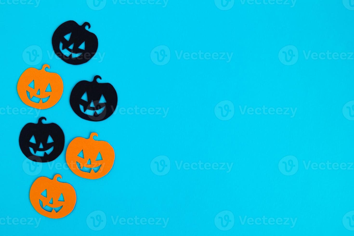 Holiday decorations for Halloween. Orange and black paper pumpkins on a blue background with copy space, top view. photo