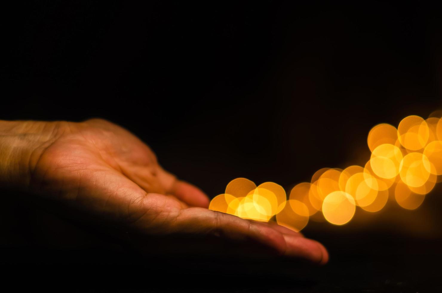 The hand releases yellow round shape bokeh light on black background. photo
