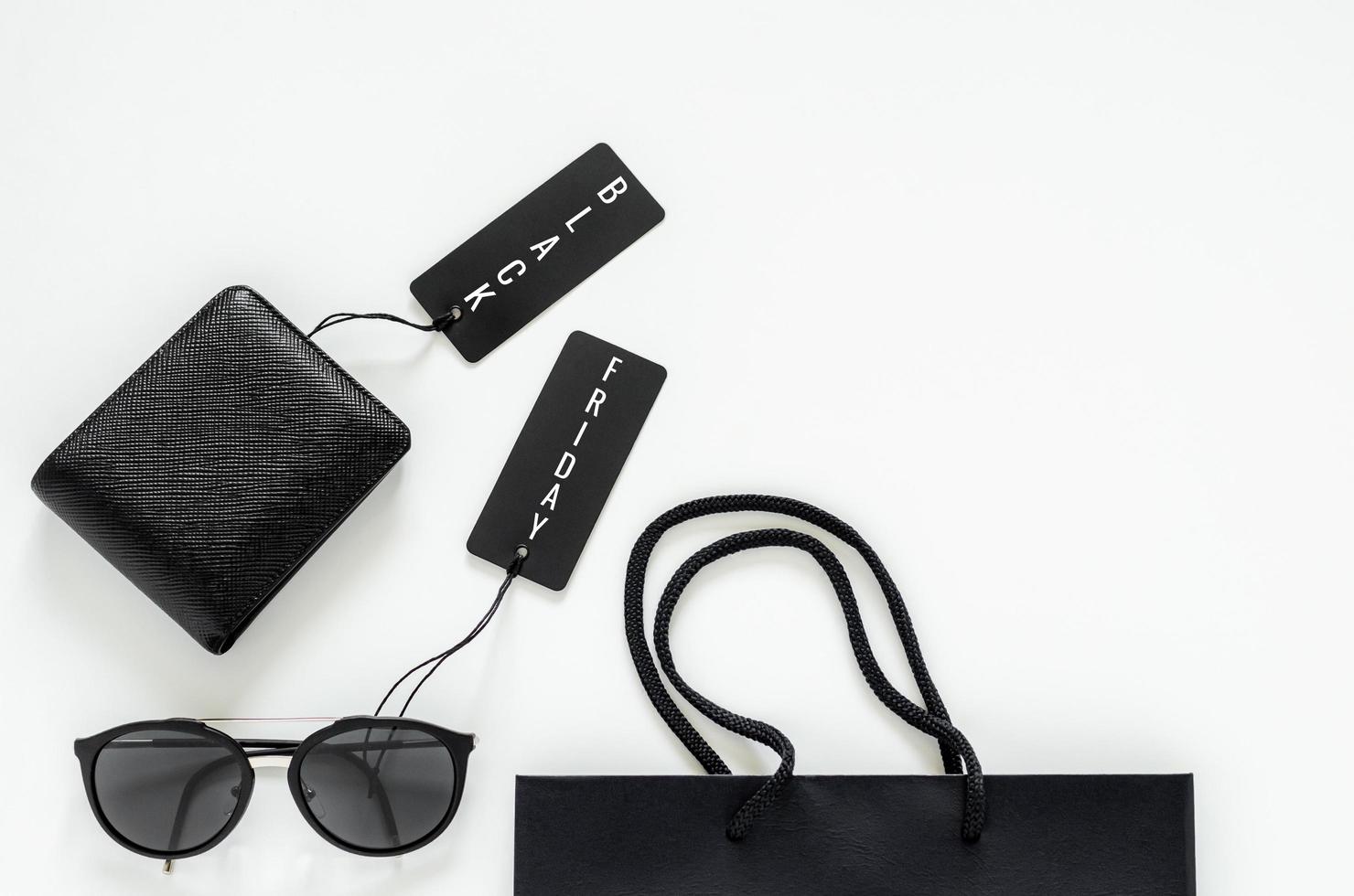 Flat lay of men stuffs - black wallet, sunglasses, price tags and shopping bag on white background for Black Friday sale concept. photo