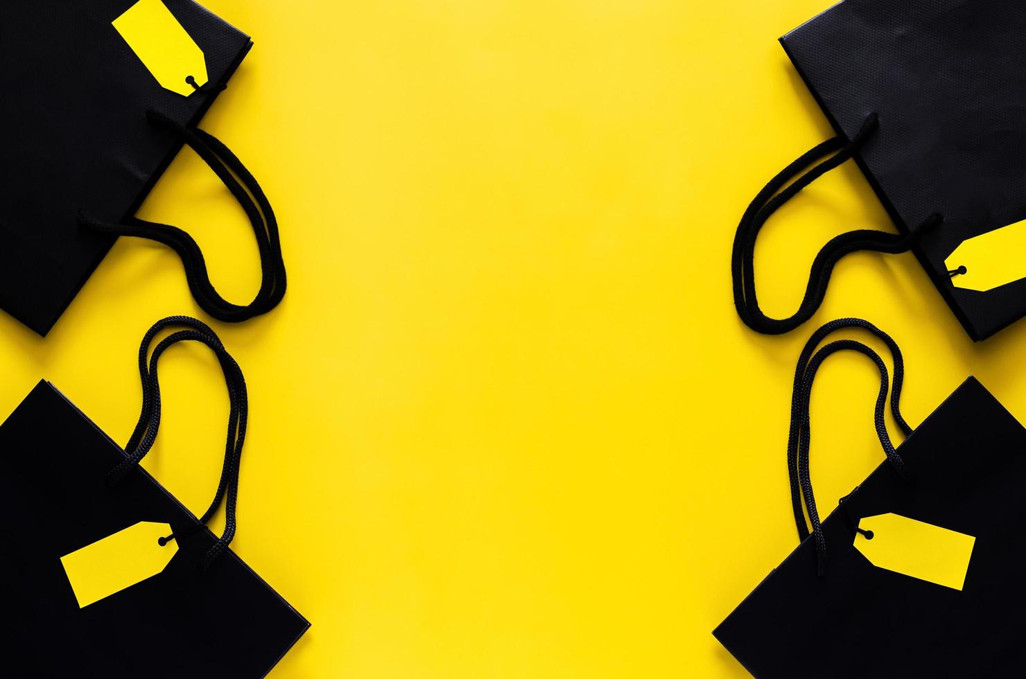 Black shopping paper bags with blank yellow price tags on yellow background for Black Friday shopping sale concept. photo