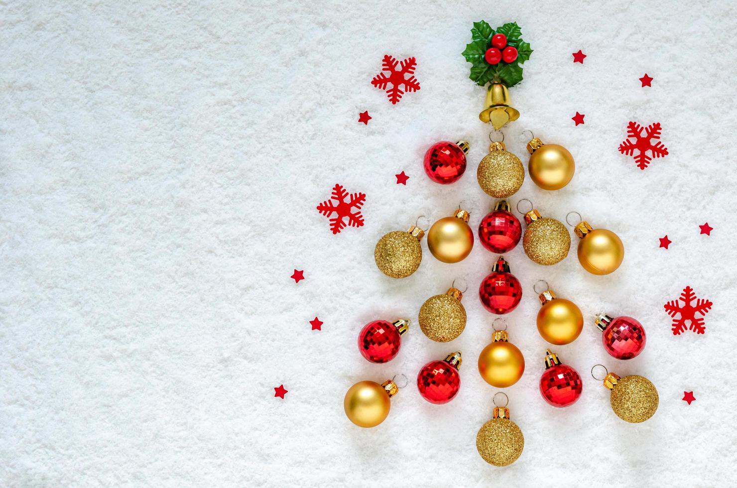 Flat lay of Christmas ornaments set as a pine tree put on snow background. photo