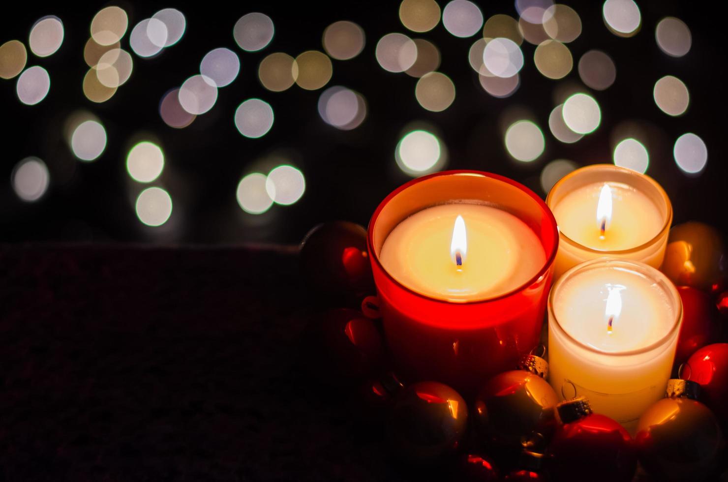 Focus and blurred burning candle with Christmas ornaments on dark and bokeh light background. photo