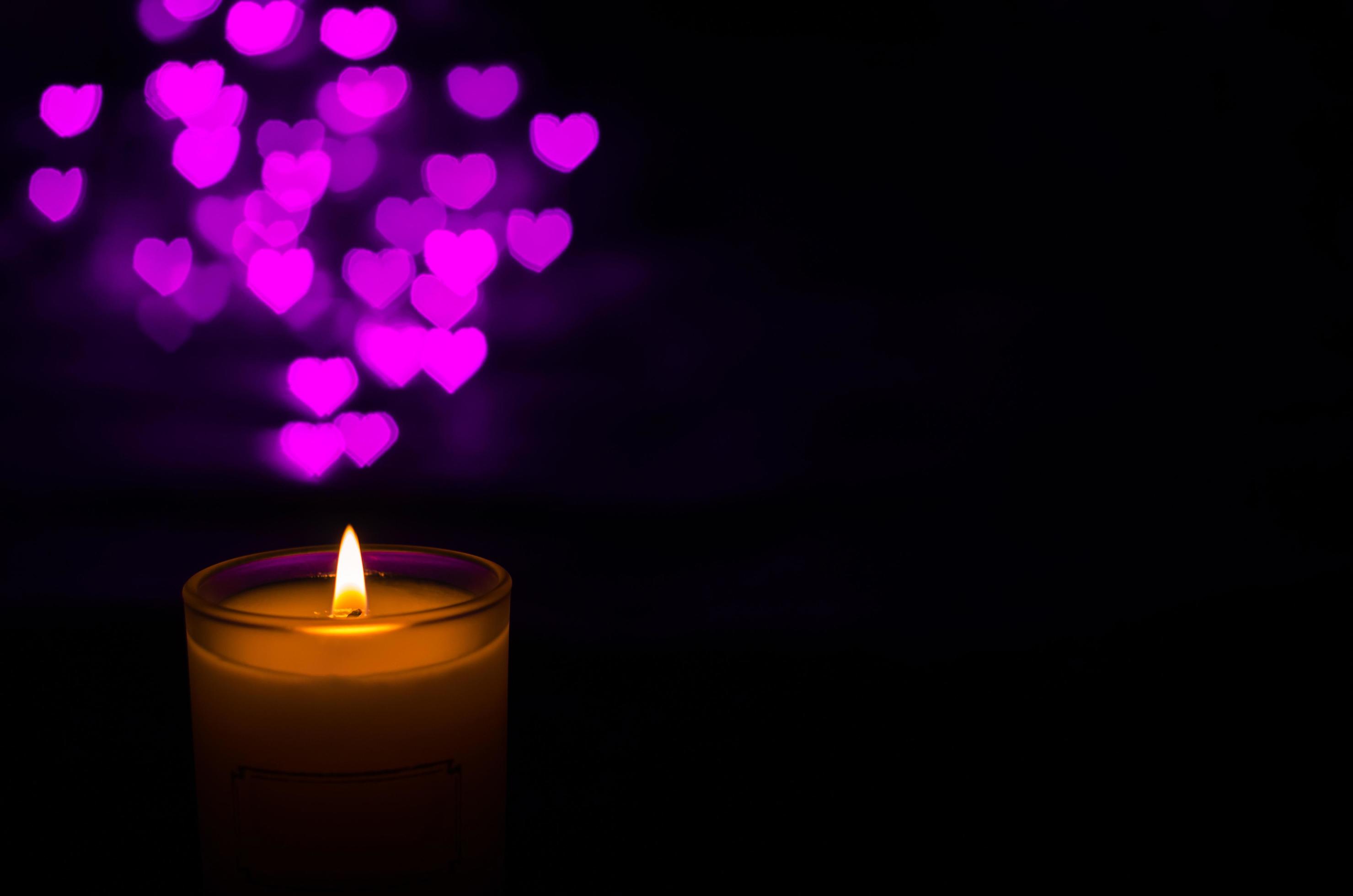 Aromatic candle with flame and love shape bokeh on dark background for