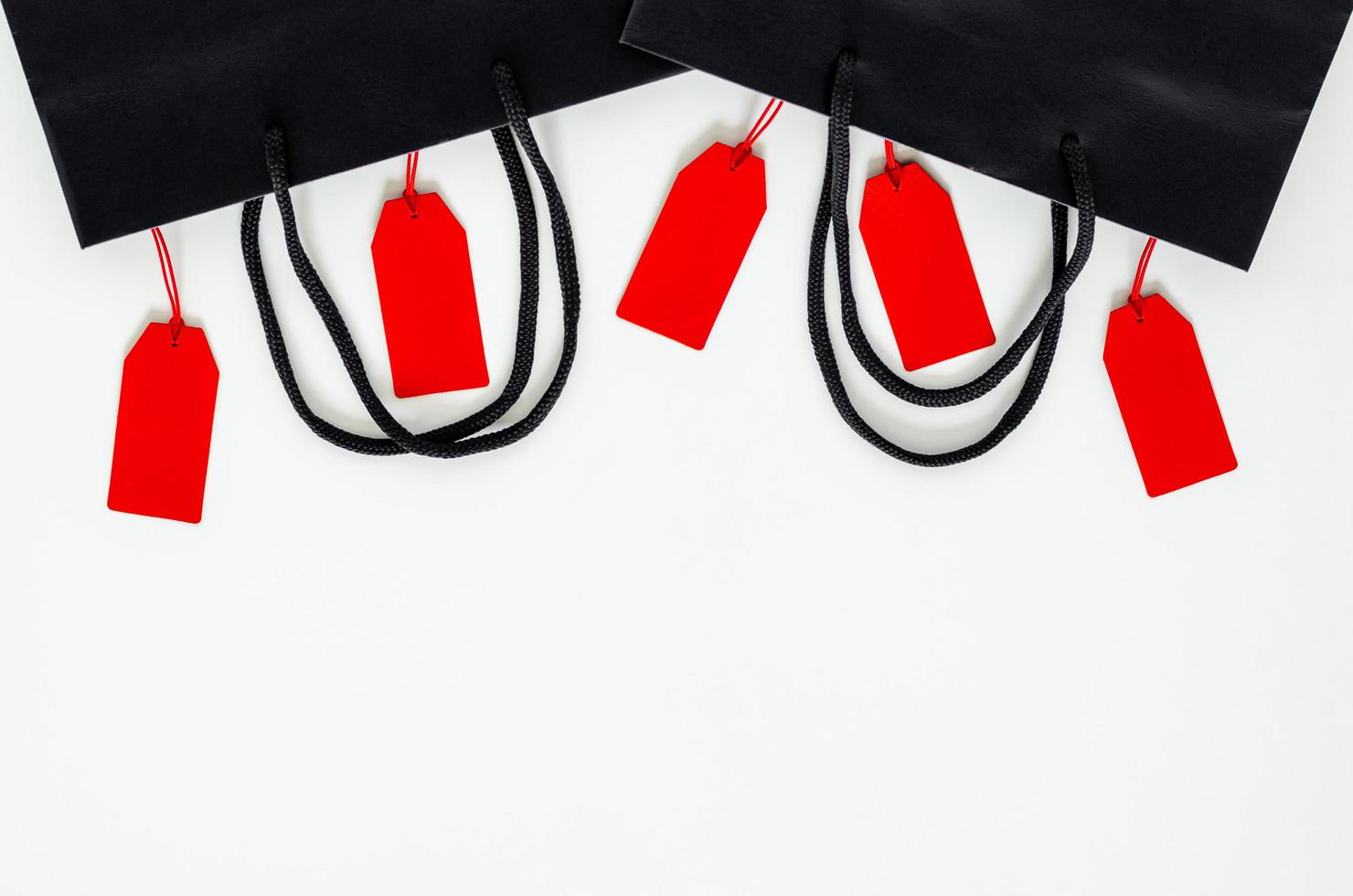 Many red price tags hanging with black paper bags on white background for Black Friday shopping sale concept. photo