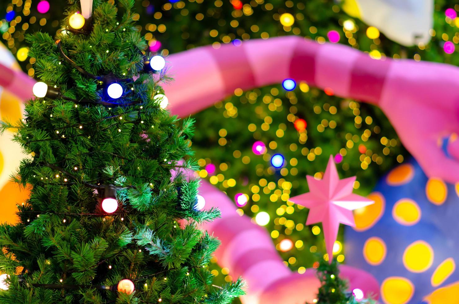 Small Christmas tree with colorful bokeh lights background from another big one for Christmas Holiday festival. photo