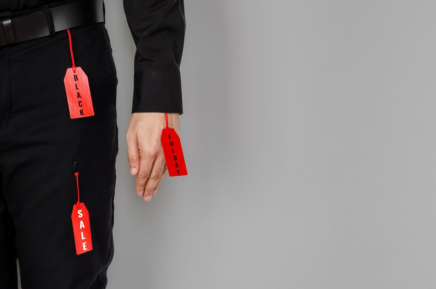 Men stuffs - black shirt, belt, long pants hanging with red price tags on gray background for Black Friday sale concept. photo