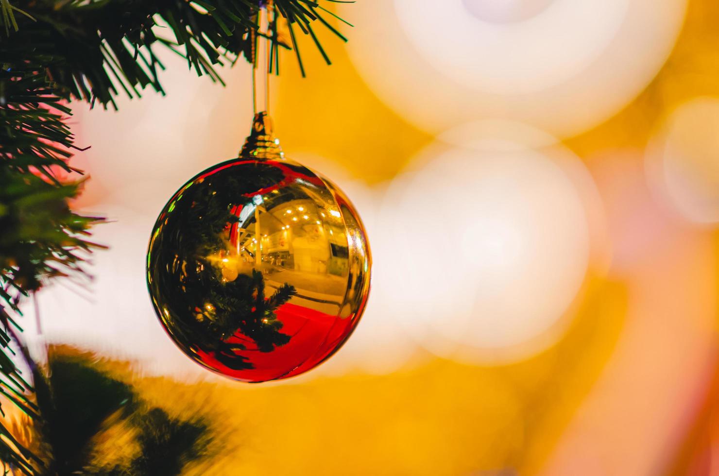 Partial focus of golden bauble hanging on Christmas tree with colorful background. photo