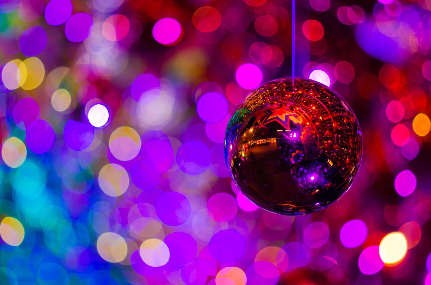 Red bauble hanging to decorate for Christmas holiday with colorful bokeh from light and other baubles. photo
