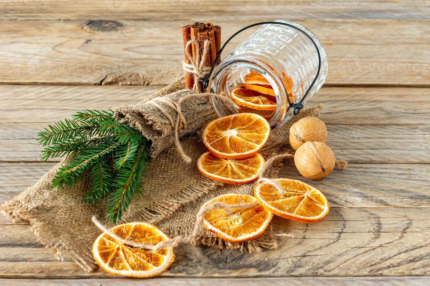 composición navideña con ramas de abeto, palitos de canela y guirnaldas hechas de rodajas secas de naranjas sobre fondo de madera. estilo rústico foto