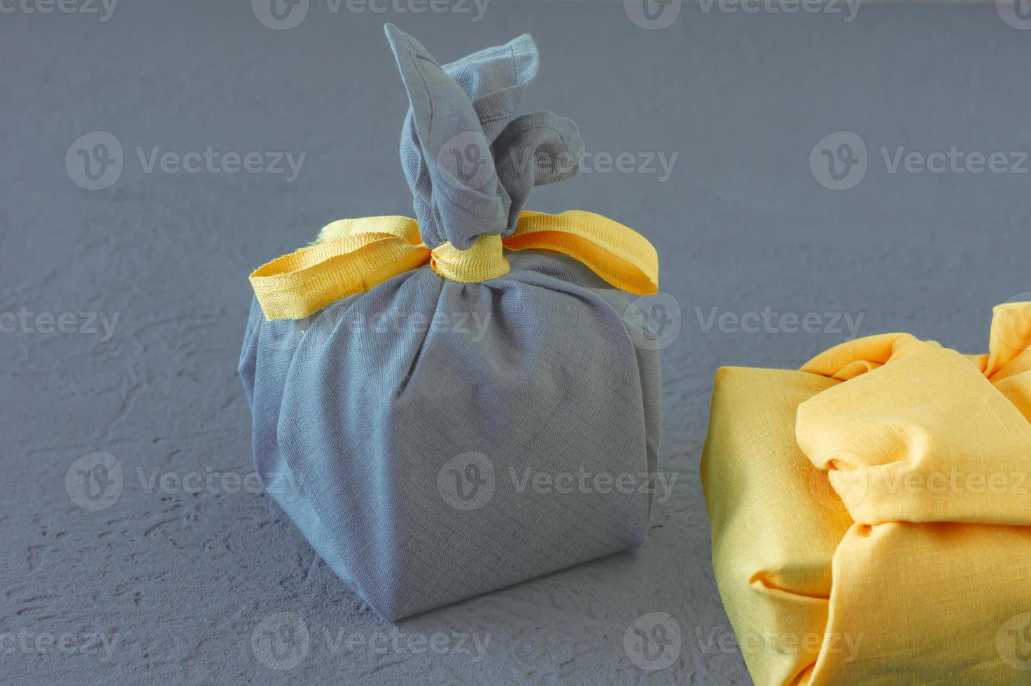 Zero waste, eco-friendly gift wrapping in traditional Japanese Furoshiki style, environmental concept, eco friendly banner. Trendy colors of the year 2021 Illuminating yellow and ultimate gray. photo