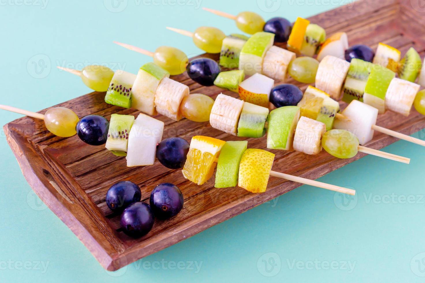 set of canapes with fruits, berries on wooden plate on blue background photo