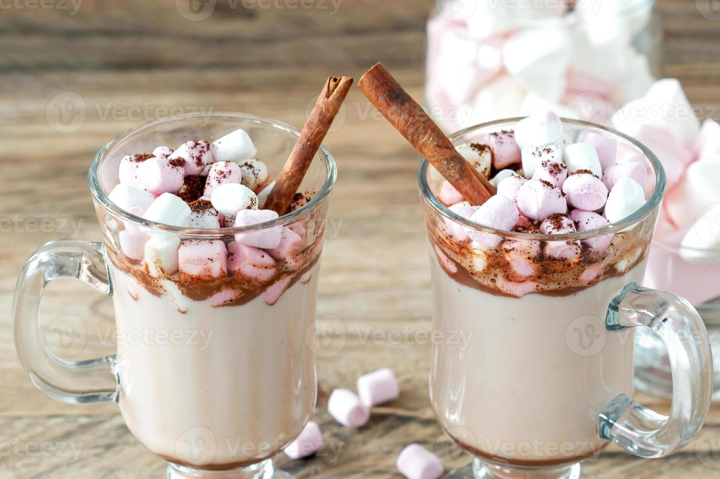 Hot cocoa or chocolate drink with marshmallow in glass mug on wooden table. Concept of cosy Christmas and New Year holidays, copy space photo
