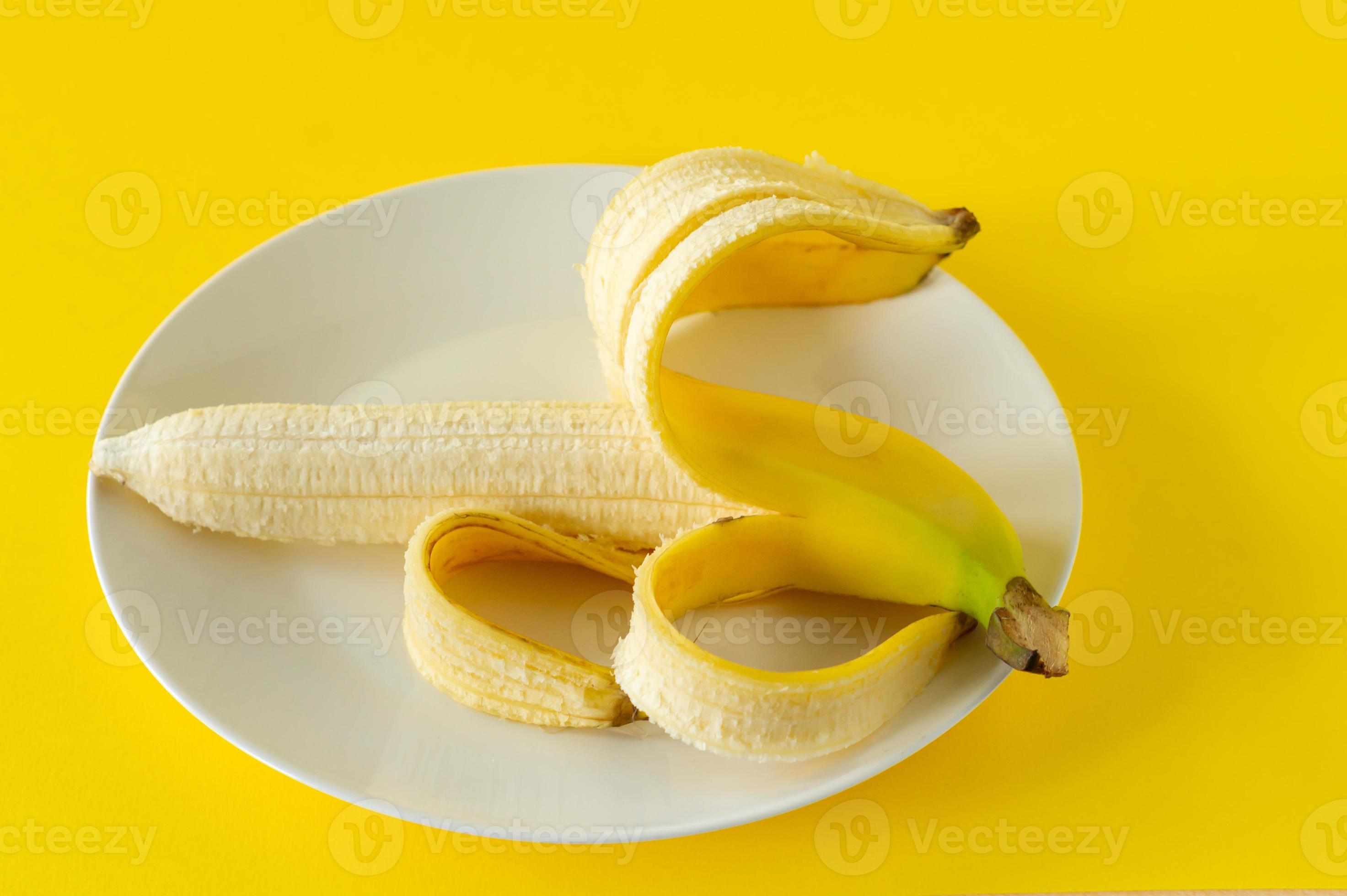 Ripe banana on black plate on yellow background. Tropical fruits for