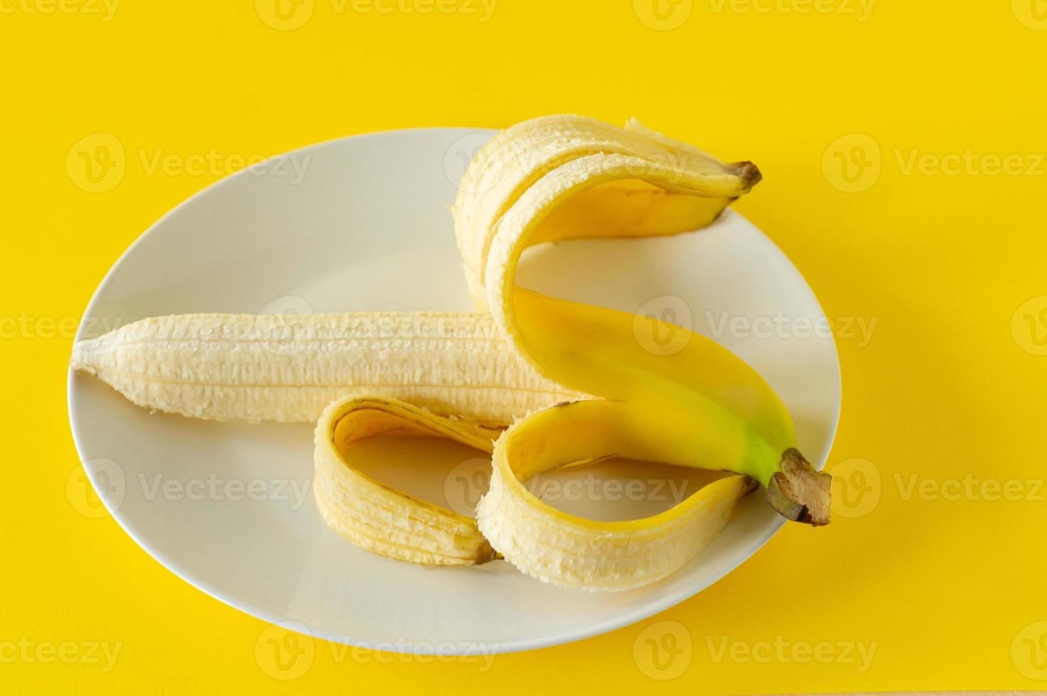 Ripe banana on black plate on yellow background. Tropical fruits for eating photo