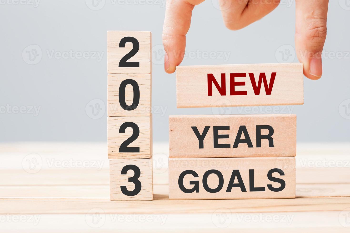 hand holding wooden block with text 2023 NEW YEAR NEW GOALS on table background. Resolution, strategy, solution, business and holiday concepts photo