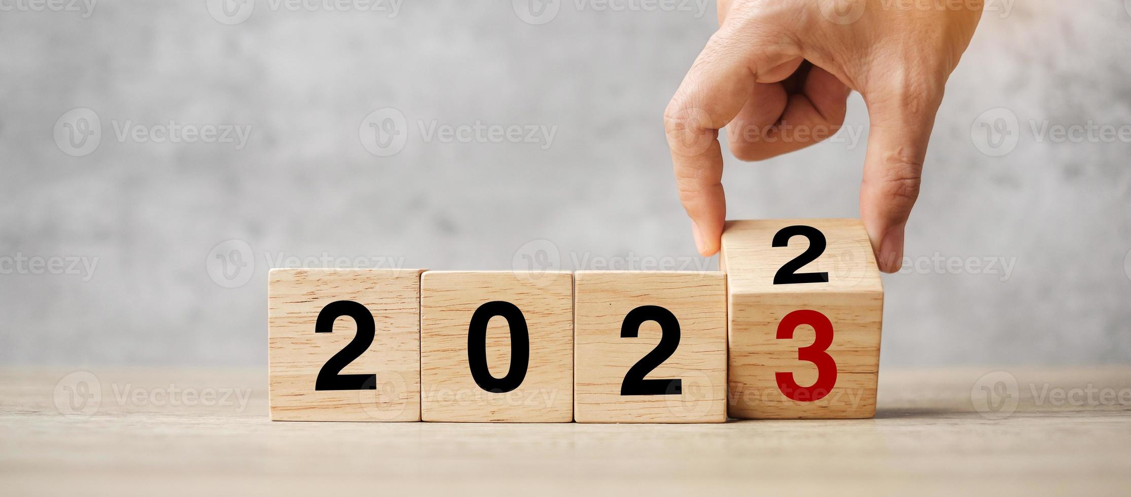 hand flipping block 2022 to 2023 text on table. Resolution, strategy, plan, goal, motivation, reboot, business and New Year holiday concepts photo