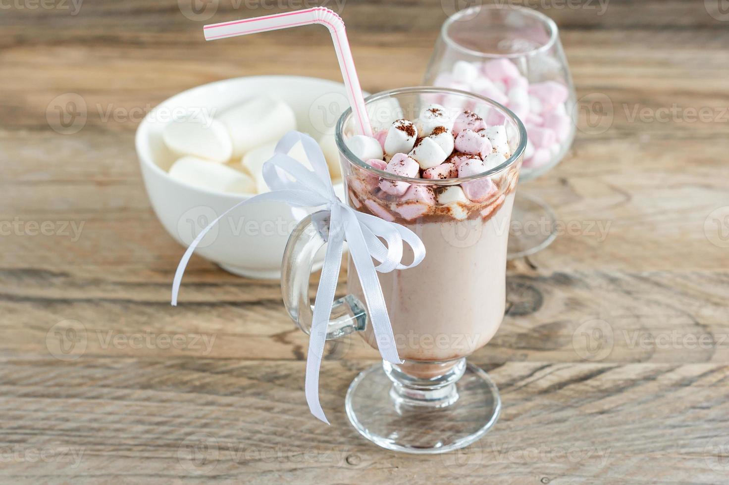 Hot cocoa or chocolate drink with marshmallow in glass mug on wooden table. Concept of cosy Christmas and New Year holidays, copy space photo