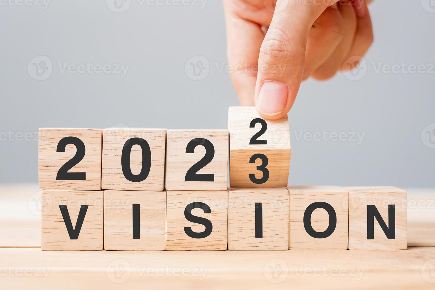 hand flipping block 2022 to 2023 VISION text on table. Resolution, strategy, goal, motivation, reboot, business and New Year holiday concepts photo