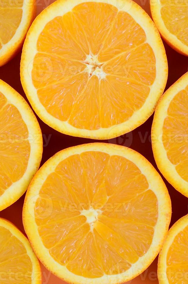 Top view of a several orange fruit slices on bright background in orange color. A saturated citrus texture image photo