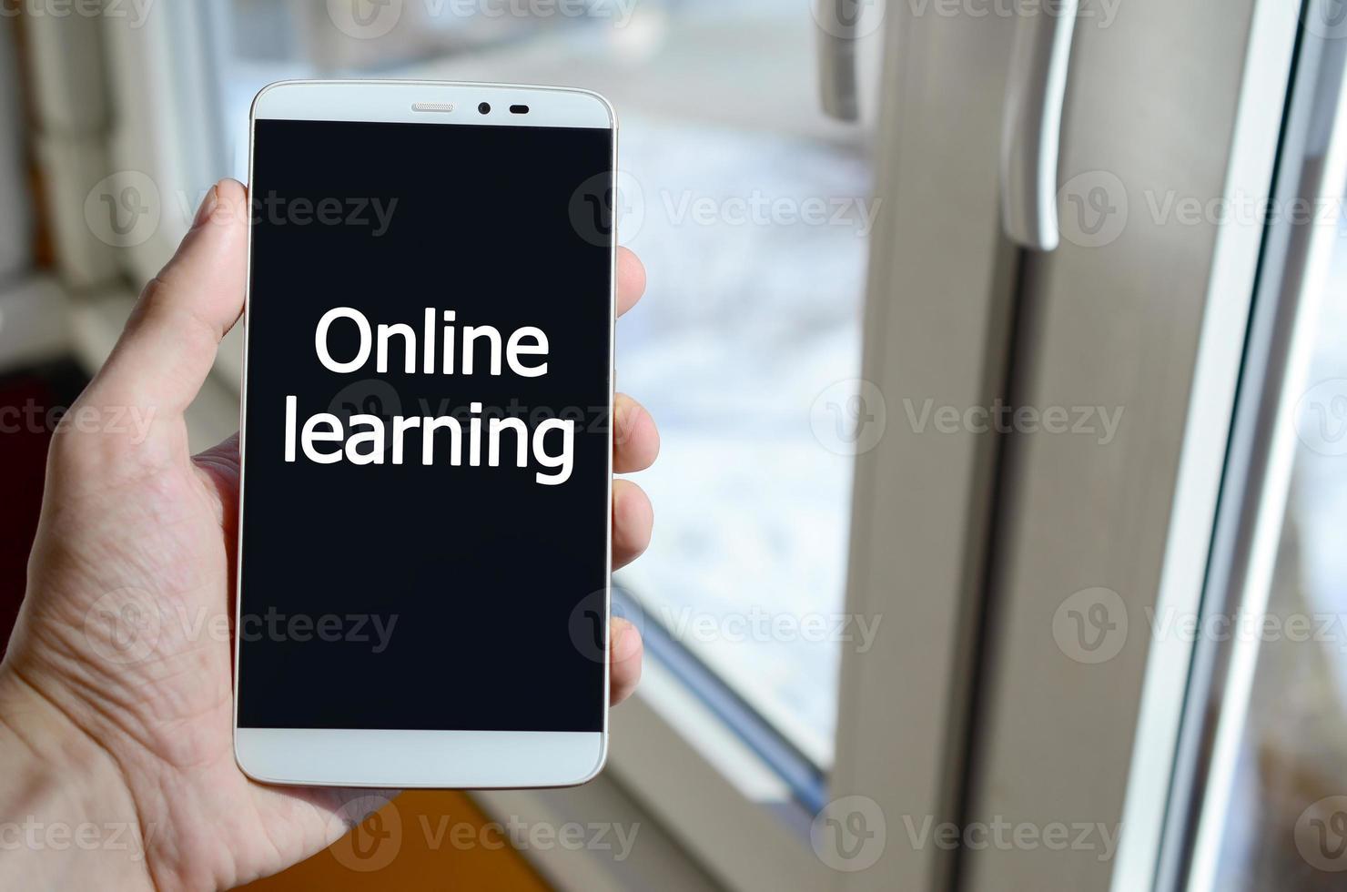 A person sees a white inscription on a black smartphone display that holds in his hand. Online learning photo