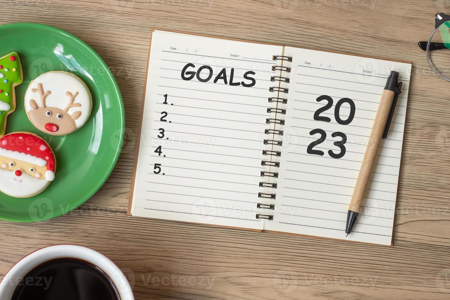 2023 GOAL with notebook, black coffee cup, Christmas cookies and pen on wood table. Xmas, Happy New Year, Resolution, To do list, Strategy and Plan concept photo