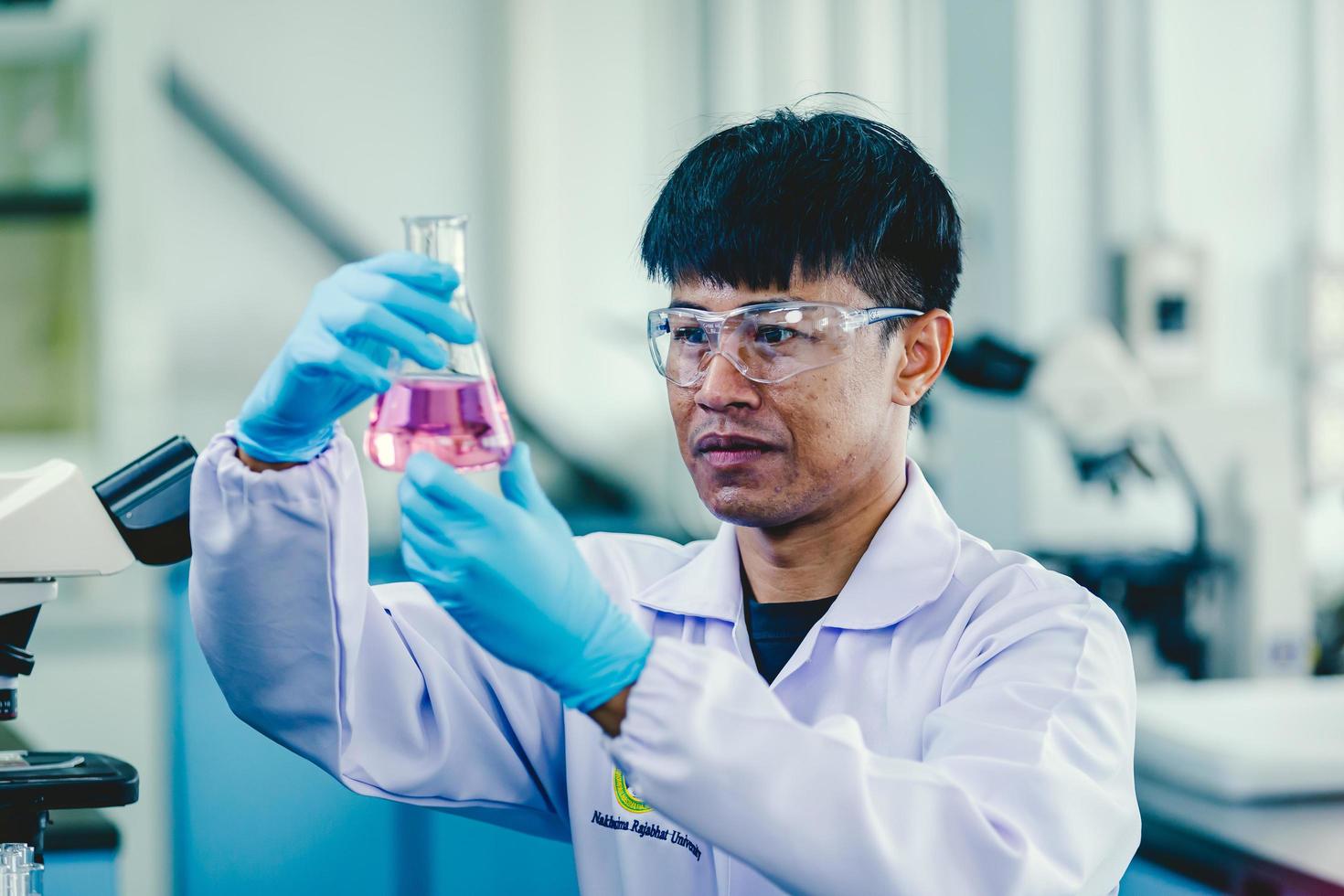 Asian male chemist wearing glasses and white lab  working in laboratory photo