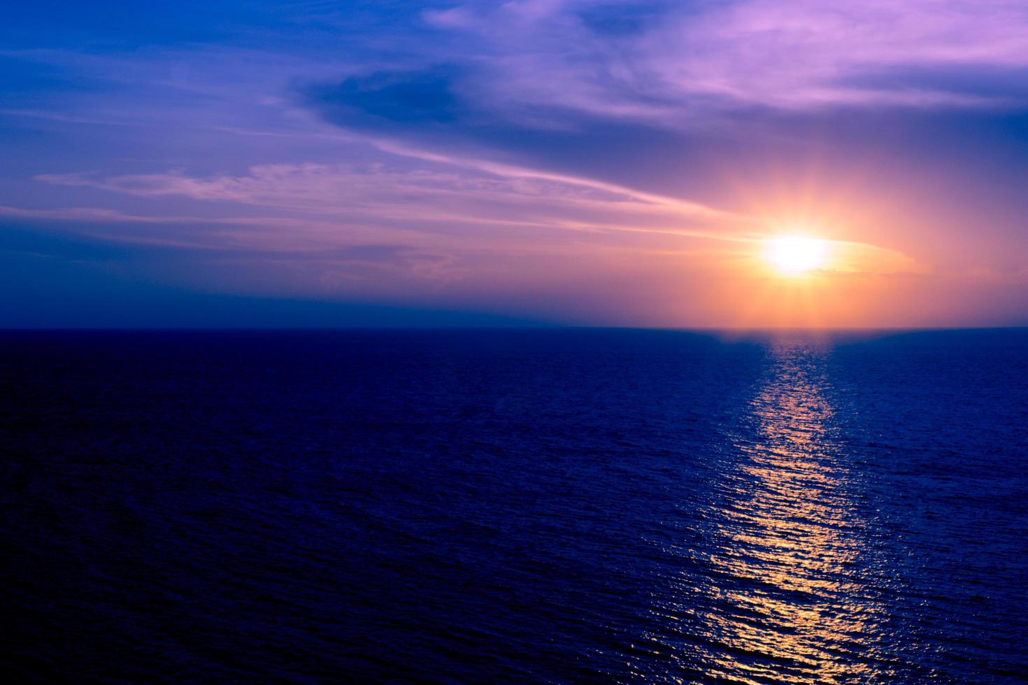 puesta de sol en el mar con nubes y reflejo de agua sobre fondo de colores oscuros. foto