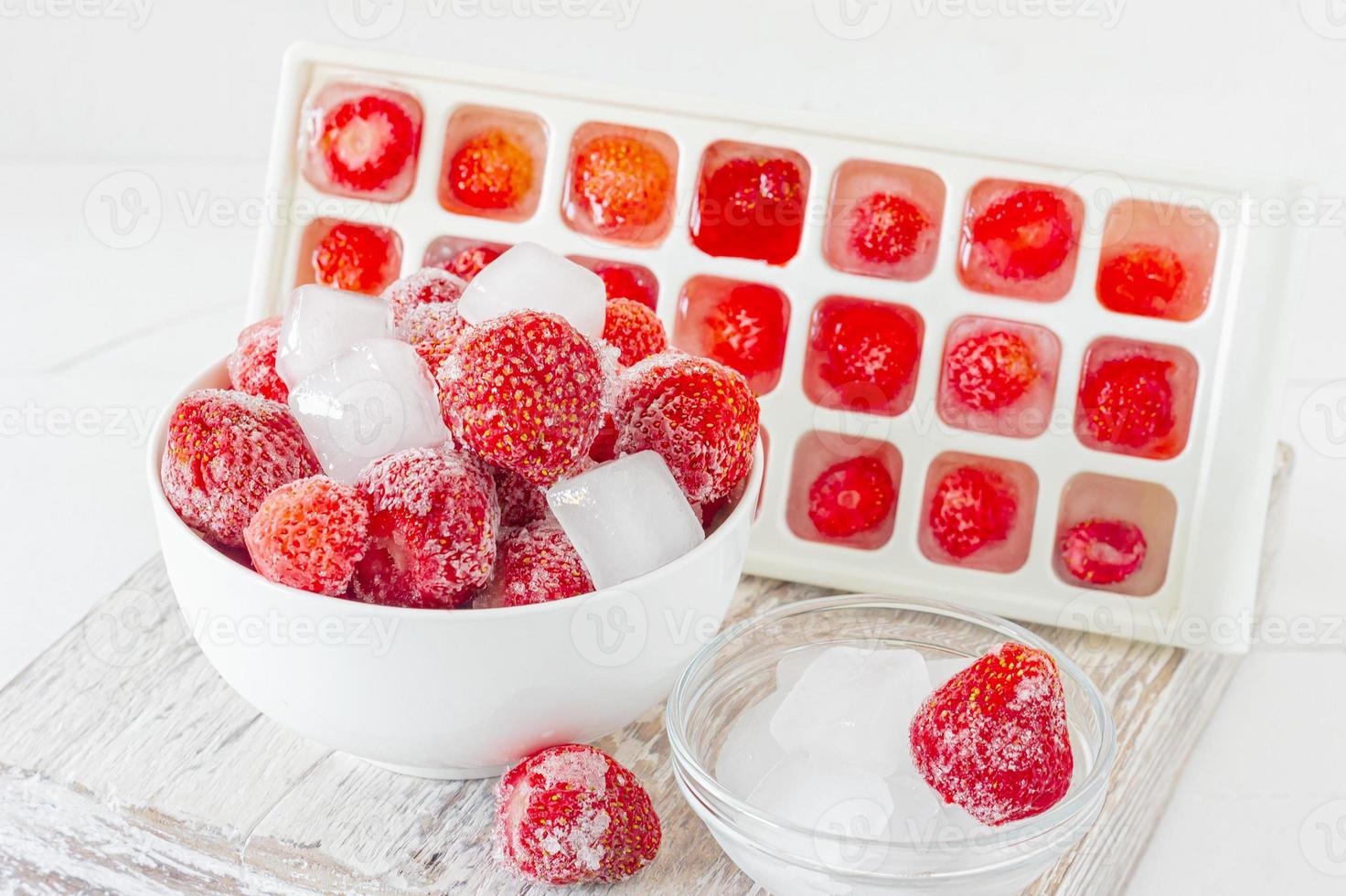 Frozen strawberry with crystals of ice on pink background photo