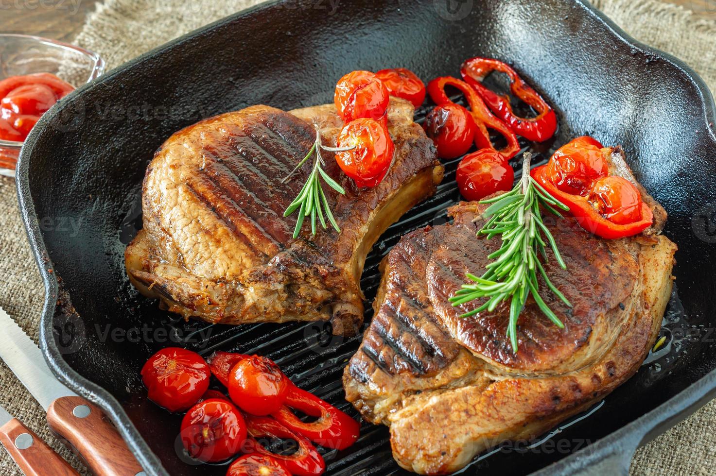 Fresh juicy roasted red meat on grill pen, with spices and vegetables. Restaurant food, delicious dish photo