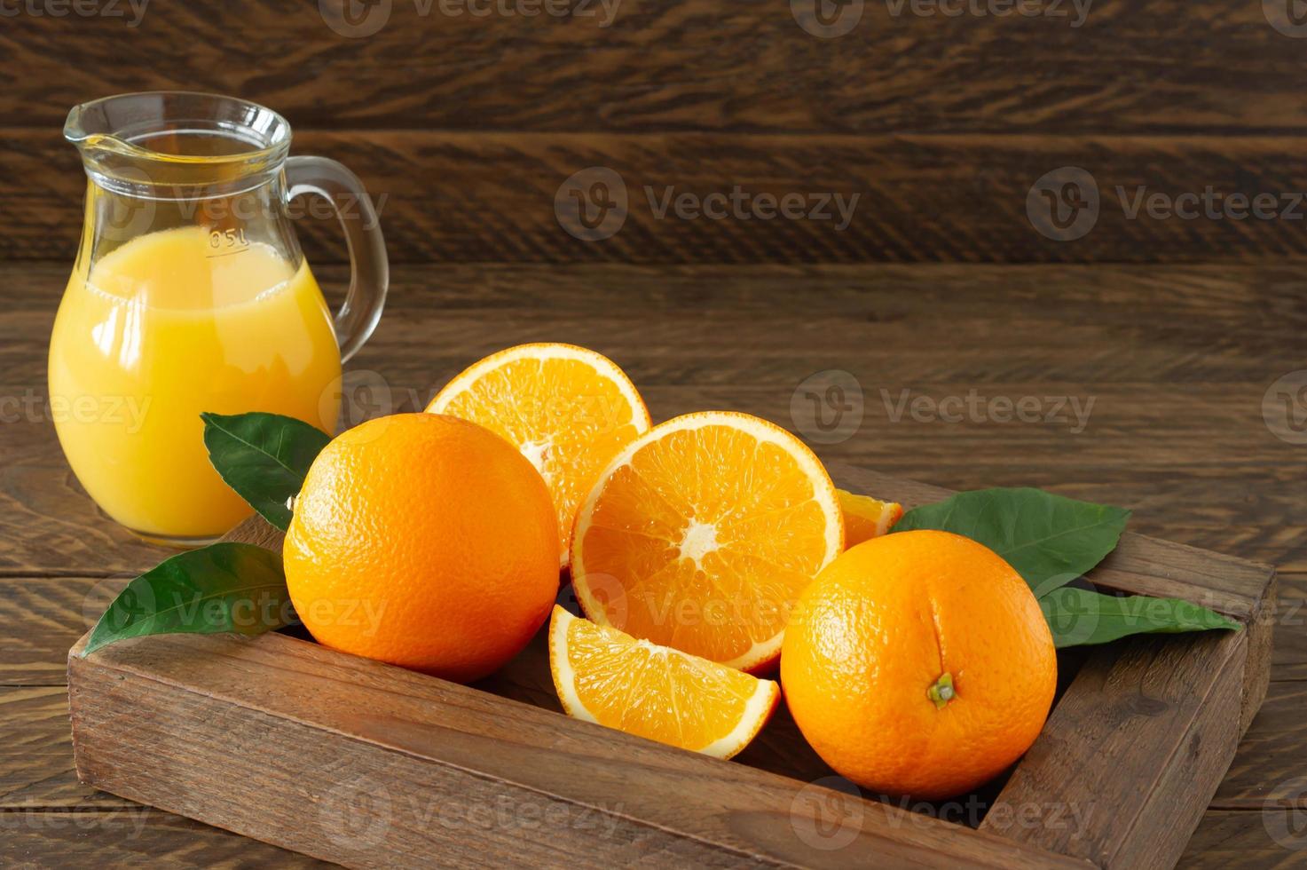 glass jar of fresh orange juice with fresh fruits on dark wooden table. photo