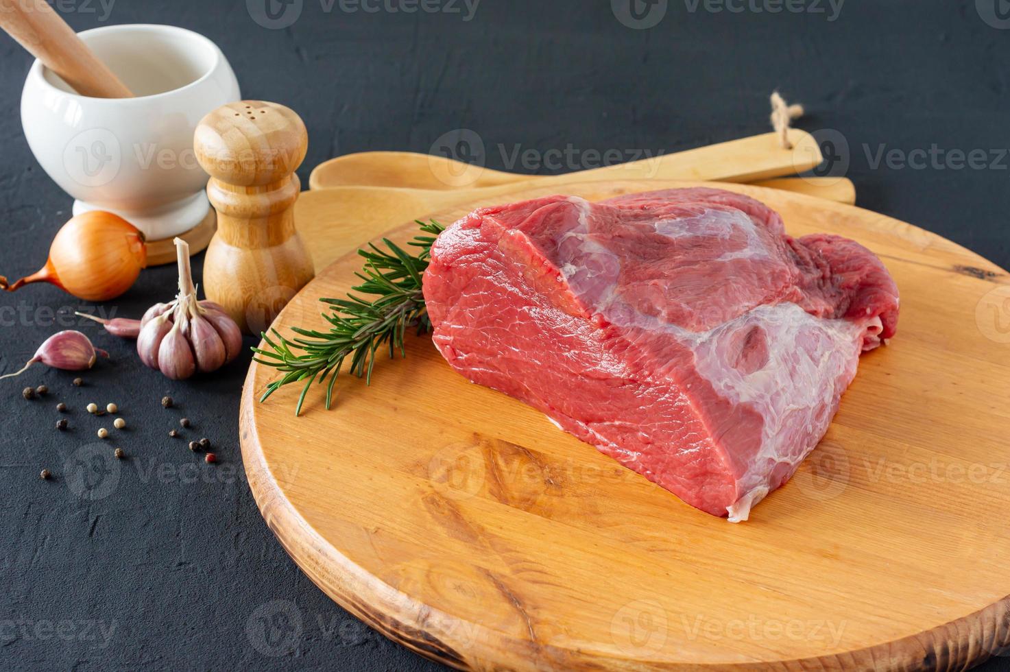 Raw whole beef sirloin on chopping board with herbs and spices photo