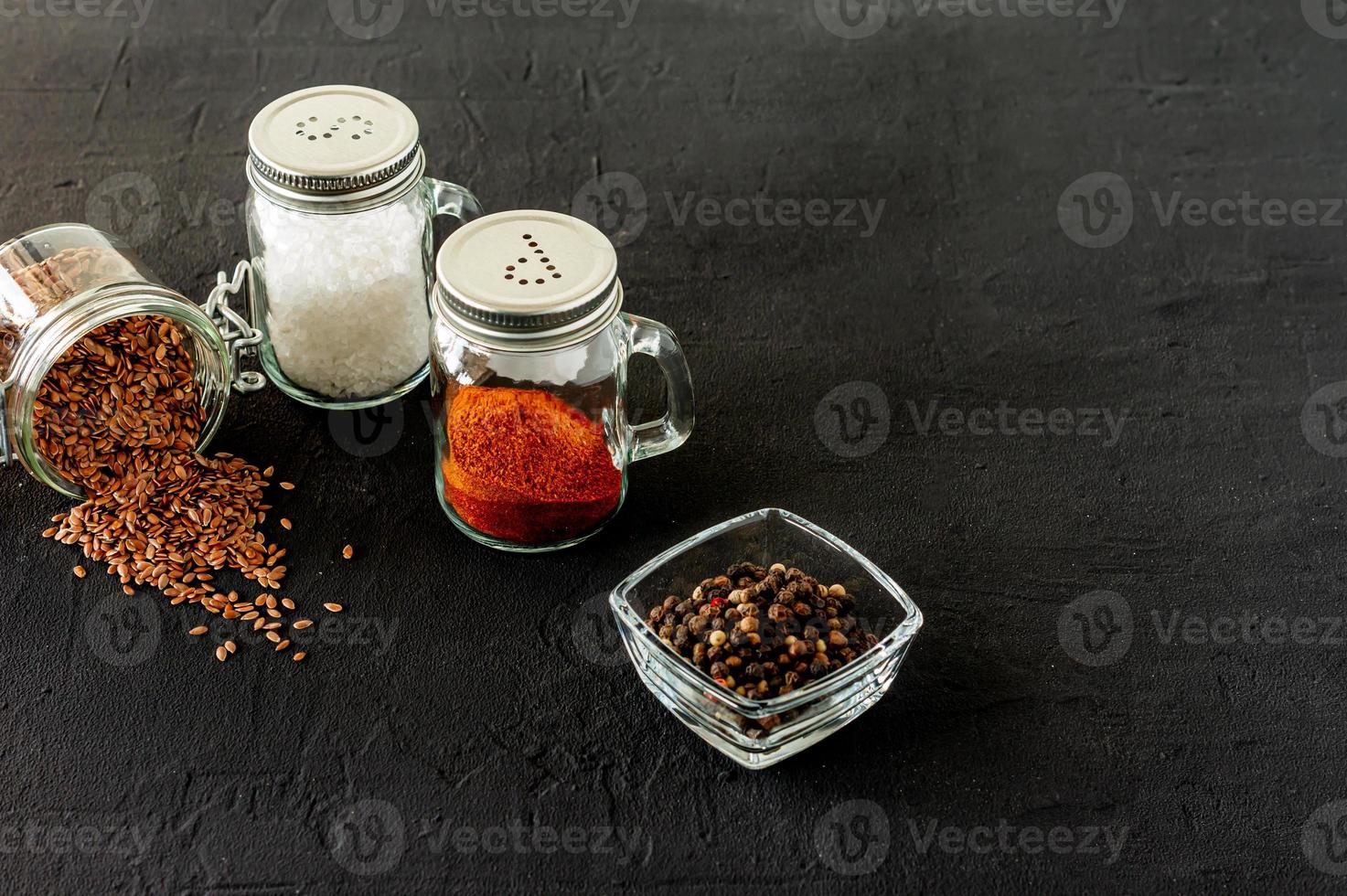 pepper and salt glass shakers on a black concrete backgroun with copy space photo