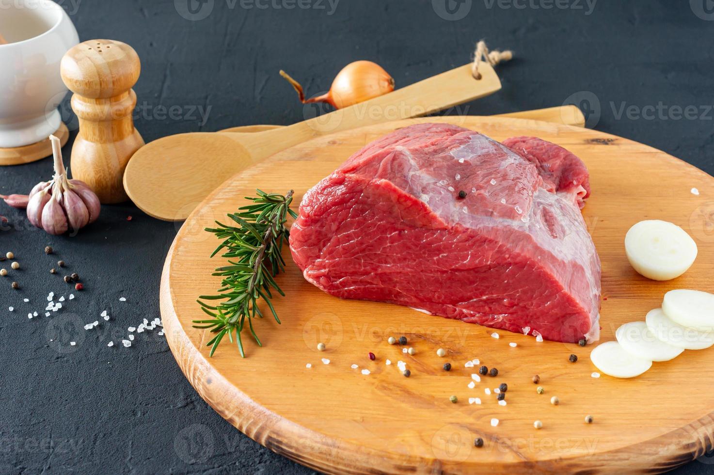 Fresh whole piece of beef steak on wooden board with herbs and spices photo