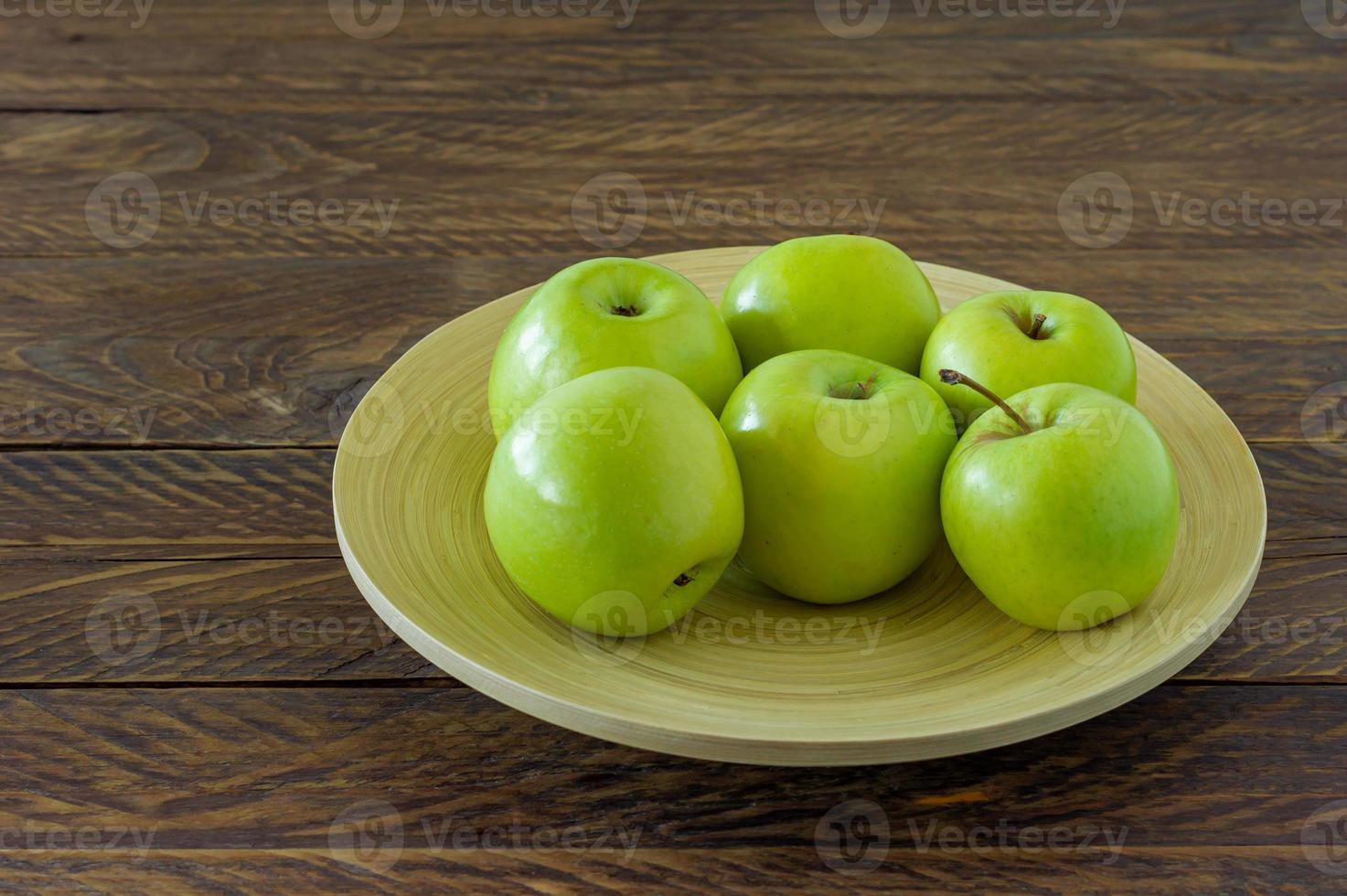 manzanas granny smith orgánicas en un plato sobre una mesa de madera. foto