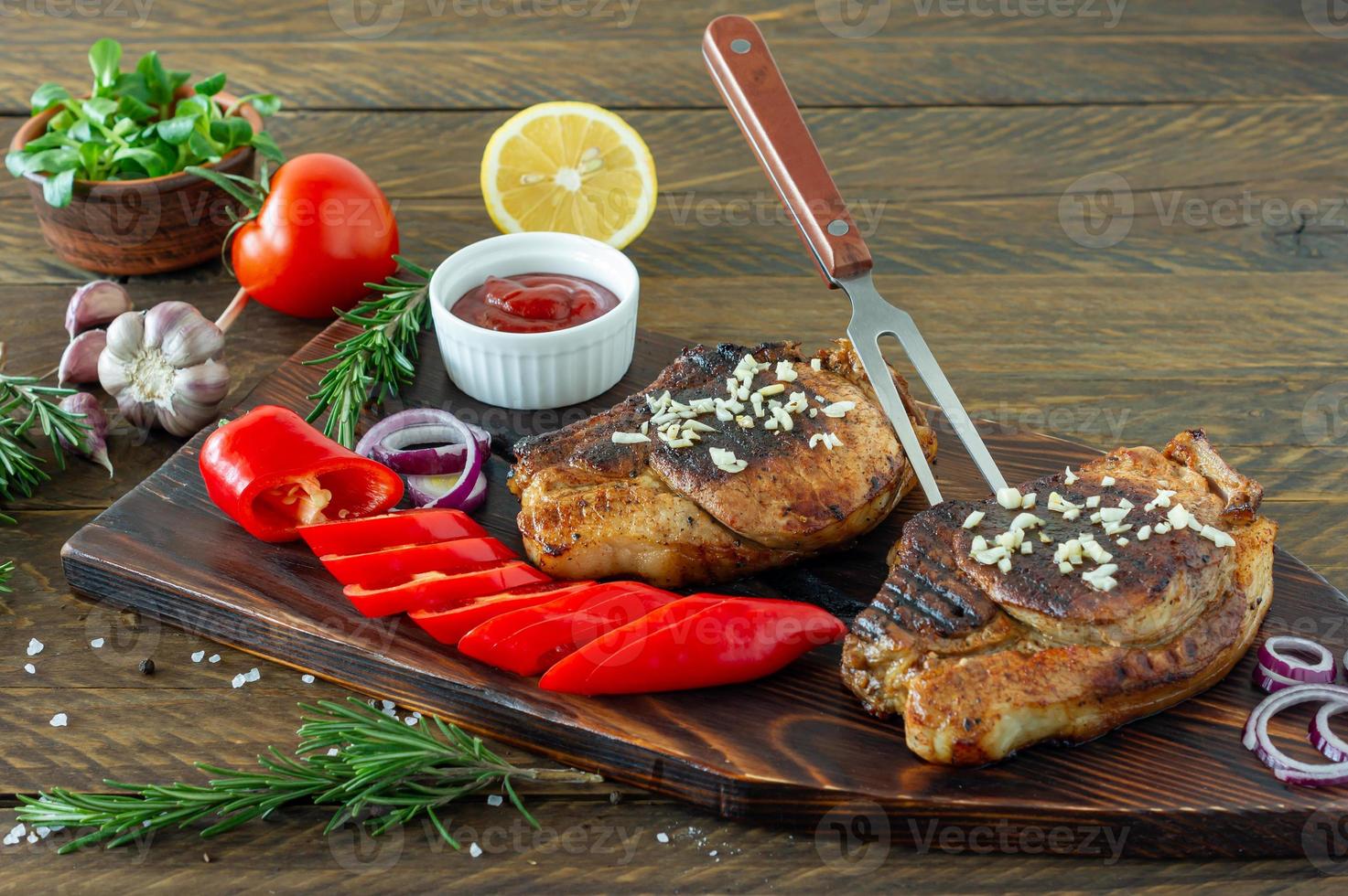 Fresh juicy roasted red meat on wooden board, with spices and vegetables. Restaurant food, delicious dish photo