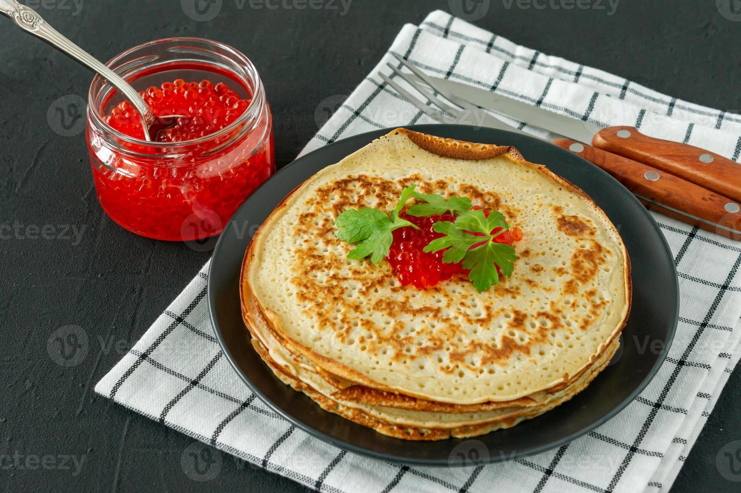 crepes rusos tradicionales blini apilados en un plato con caviar rojo sobre fondo de madera. Maslenitsa comida tradicional del festival ruso. comida rusa, cocina rusa. de cerca. foto