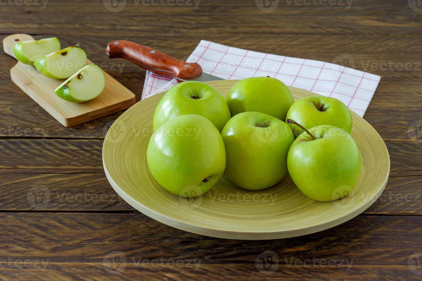 Organic Granny Smith apples on a plate on wooden table. photo