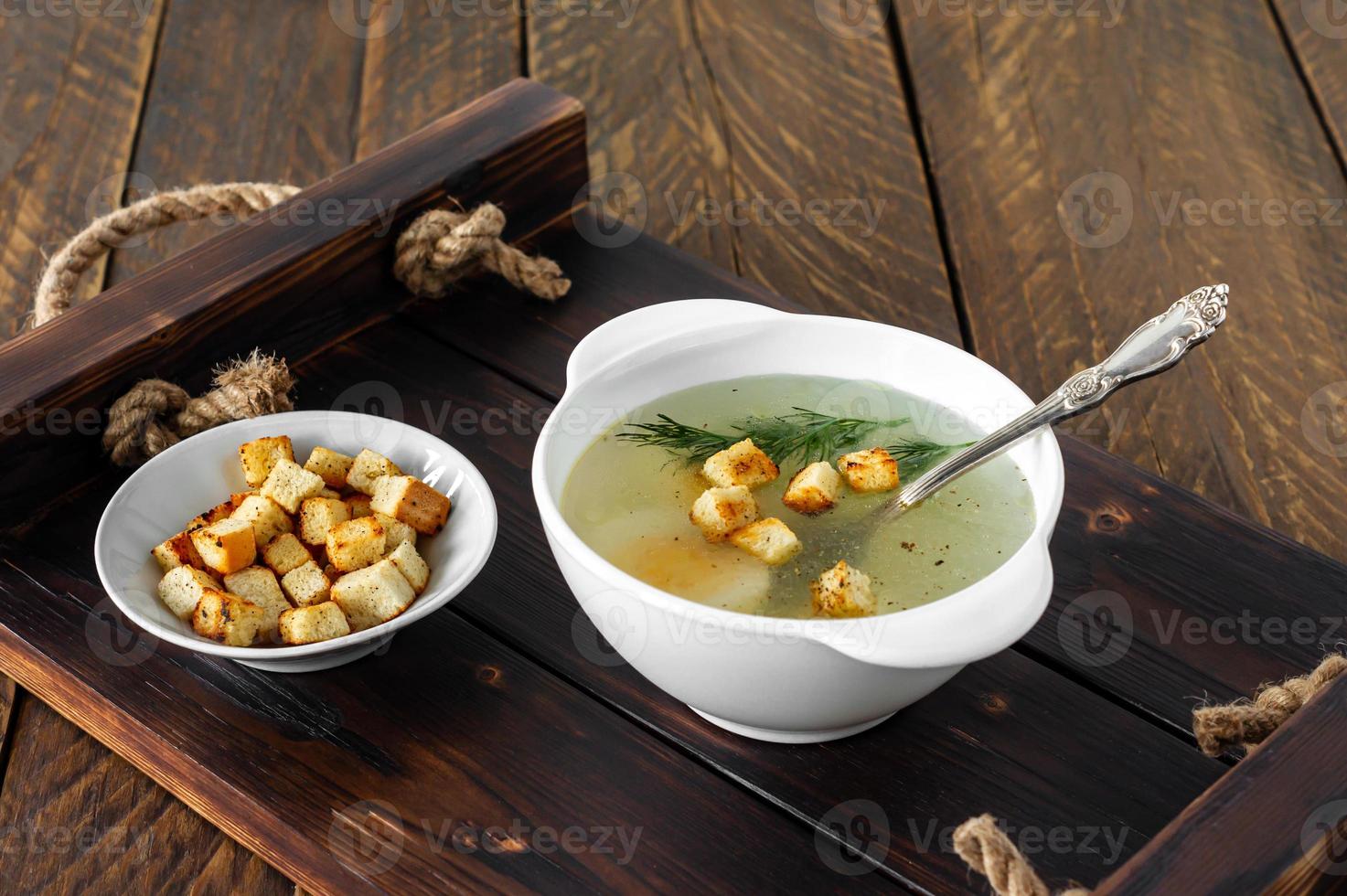 Chicken soup with vegetables in white bowl. Tasty homemade broth on a wooden background photo