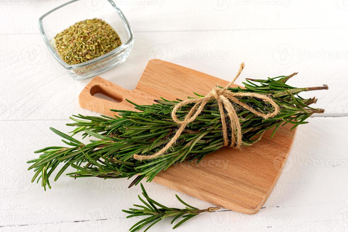 Rosemary bound lie on a cutting board nex to the dry seeds on a wooden board photo