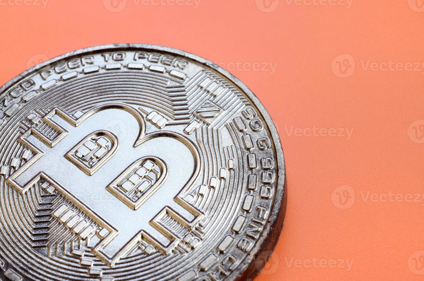Chocolate product in the form of physical bitcoin lies on an orange plastic background. Model of the crypto currency in the edible form photo