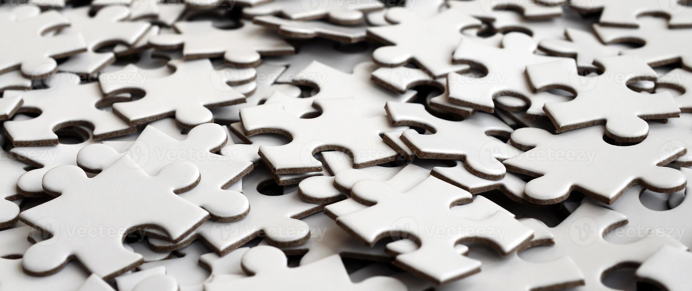 Close-up of a pile of uncompleted elements of a white puzzle. A huge number of rectangular pieces from one large white mosaic photo