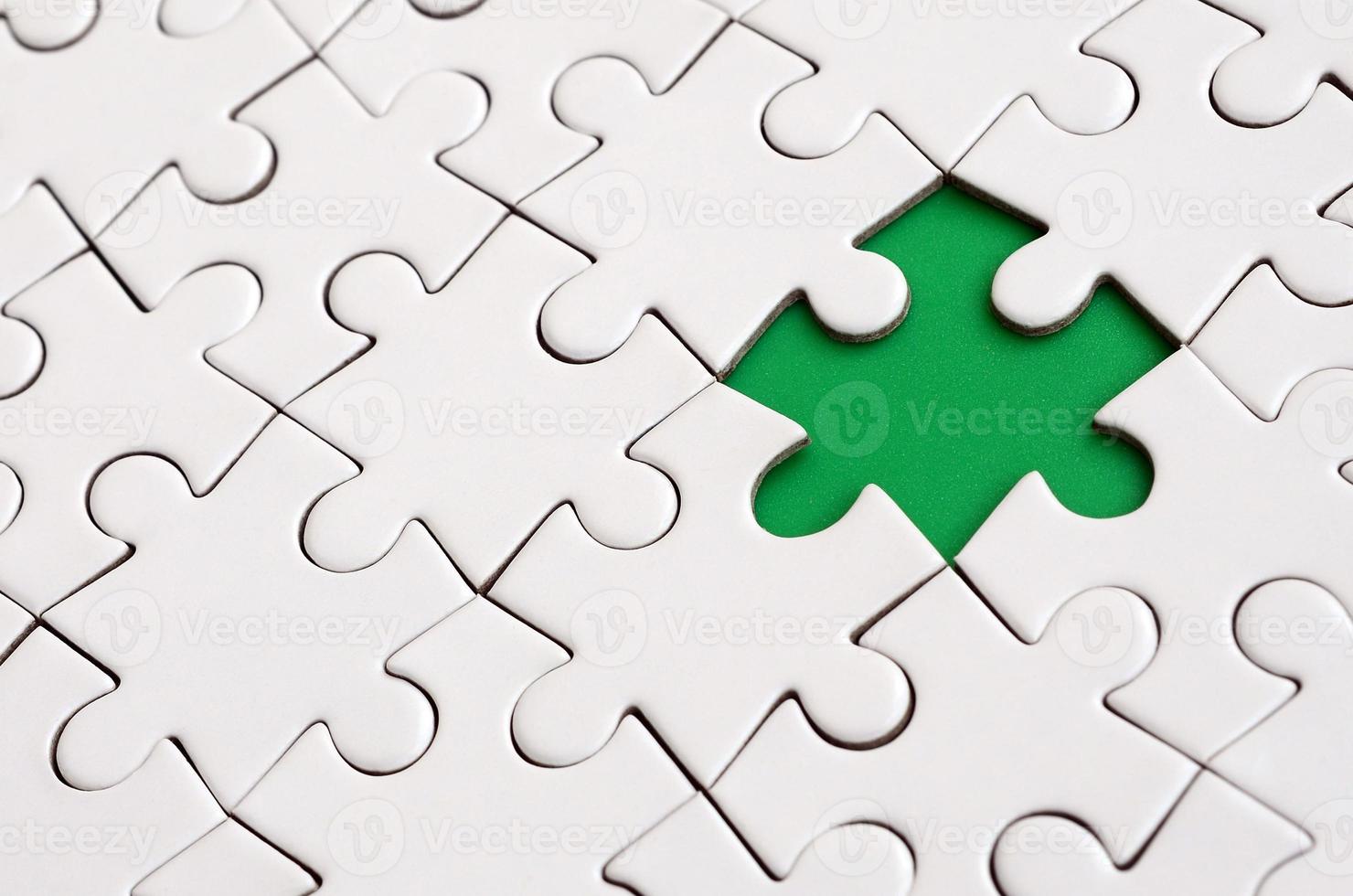 Close-up texture of a white jigsaw puzzle in assembled state with missing elements forming a green pad for text. Copy space photo