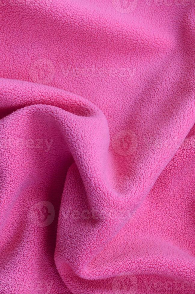 The blanket of furry pink fleece fabric. A background of light pink soft plush fleece material with a lot of relief folds photo