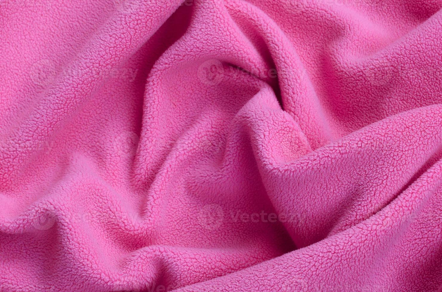 The blanket of furry pink fleece fabric. A background of light pink soft plush fleece material with a lot of relief folds photo