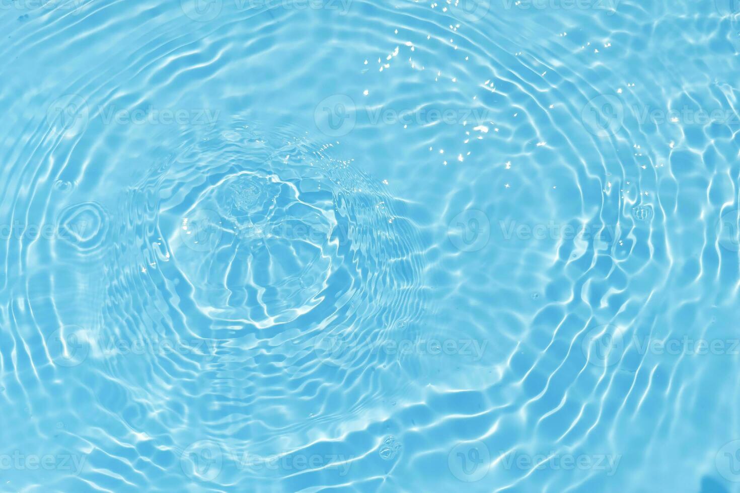 Defocus blurred transparent blue colored clear calm water surface texture with splash, bubble. Shining blue water ripple background. Surface of water in swimming pool. Blue bubble water shining. photo