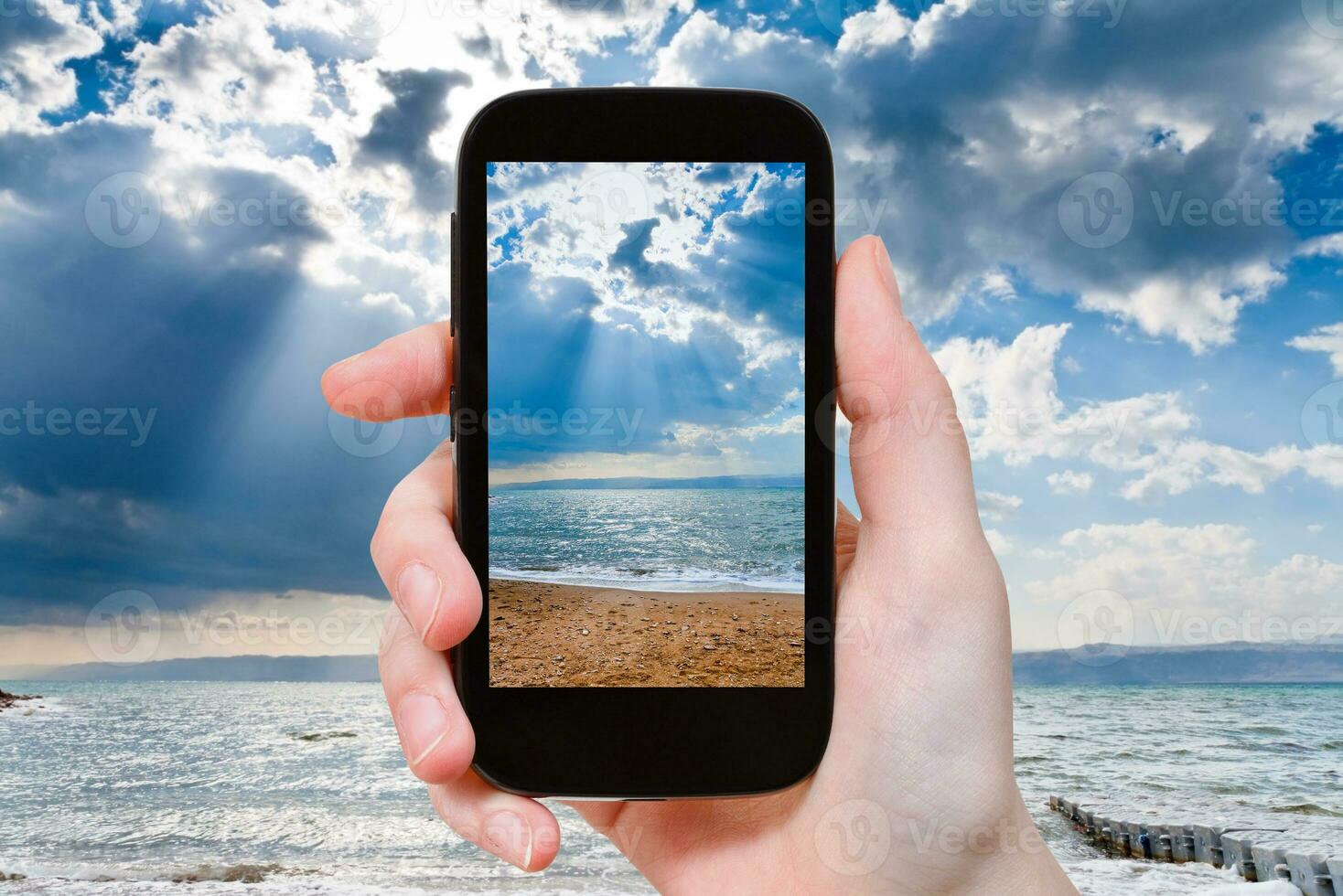 tourist taking photo of sunbeams over Dead Sea