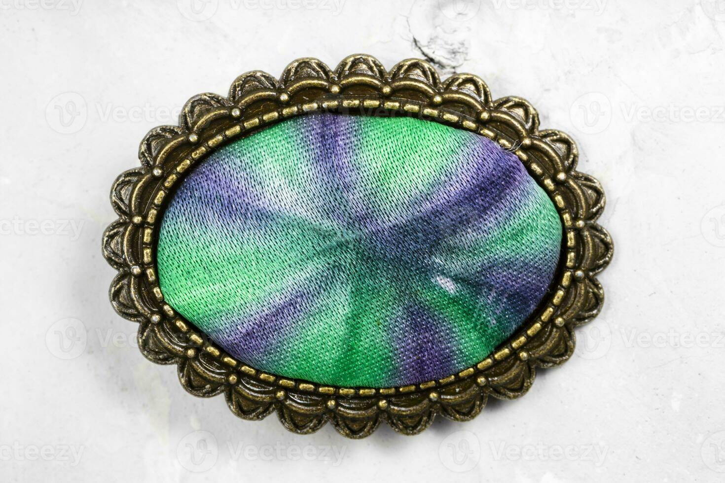 bronze brooch with hand-colored silk batik on gray photo