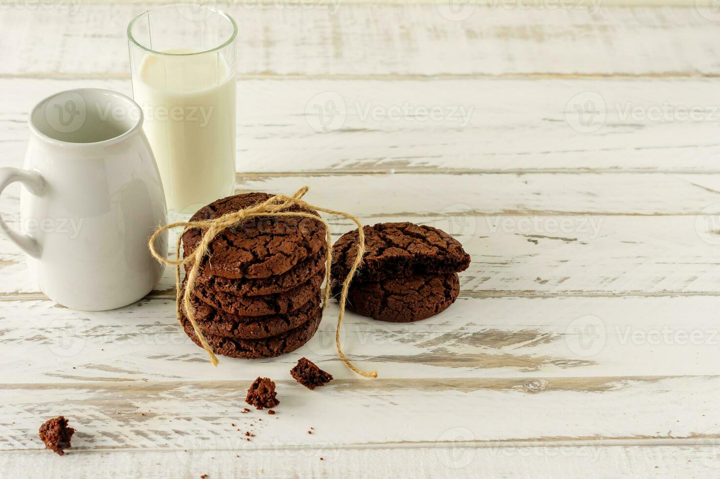 Chocolate cookies for breakfast with a glass of milk on a white wooden table. photo