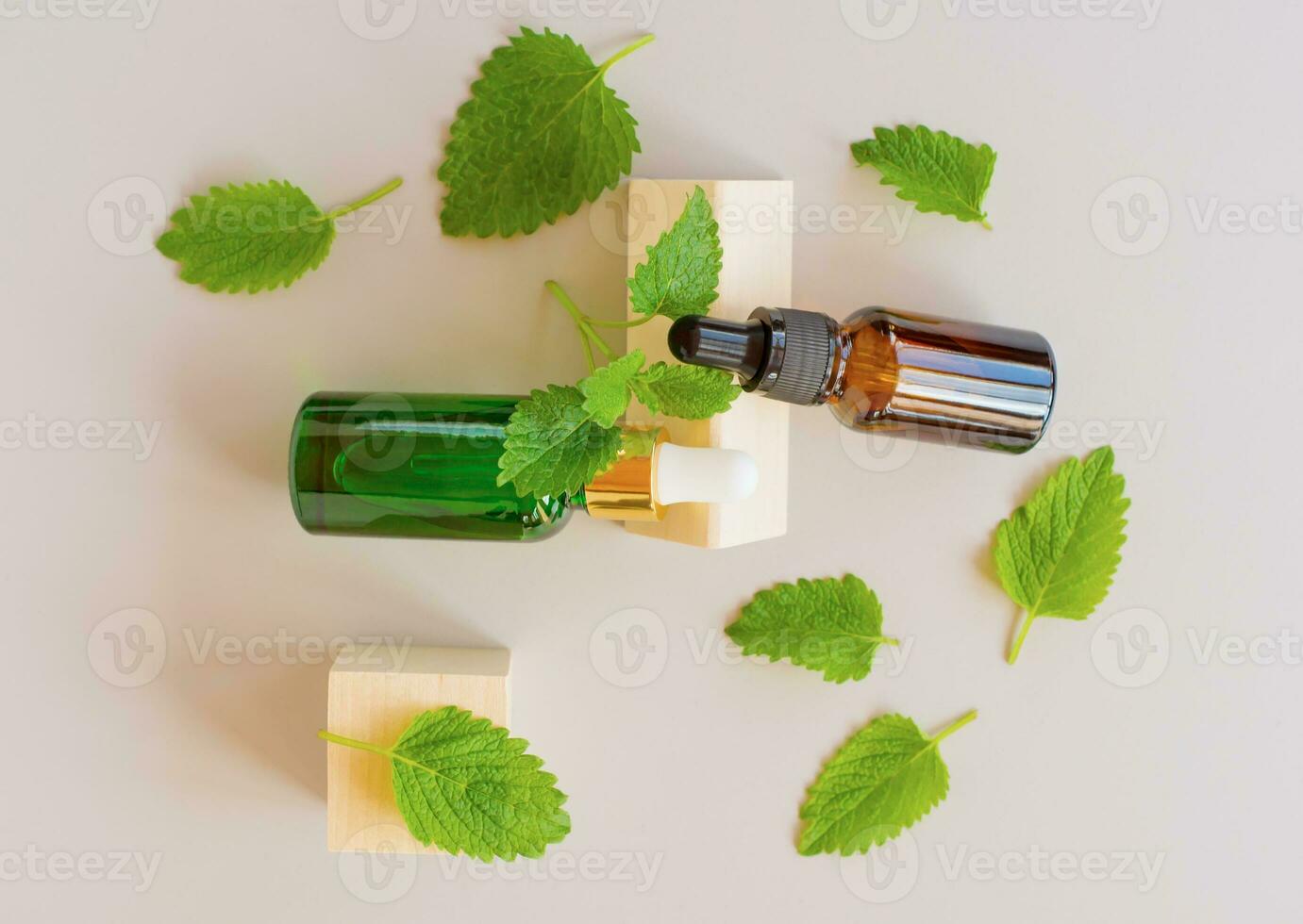 Top view of fresh green mint or spearmint leaves and glass dropper bottles of mint essential oil on gray background. Natural herbal medical aromatic plant concept. photo